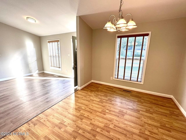 unfurnished room with a chandelier, light hardwood / wood-style flooring, and plenty of natural light