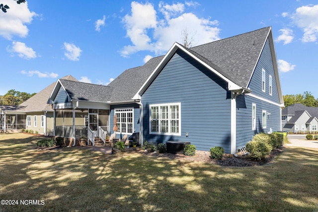 rear view of property with a sunroom and a lawn