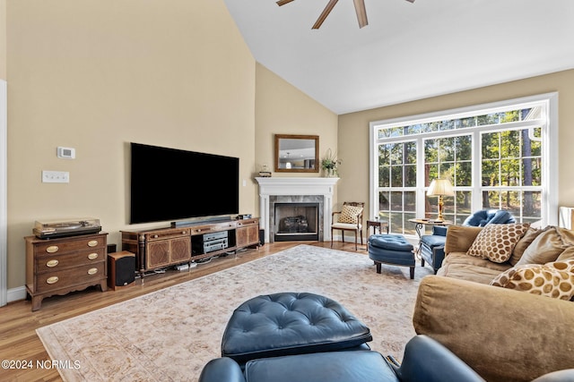 living room featuring hardwood / wood-style flooring, ceiling fan, a premium fireplace, and vaulted ceiling