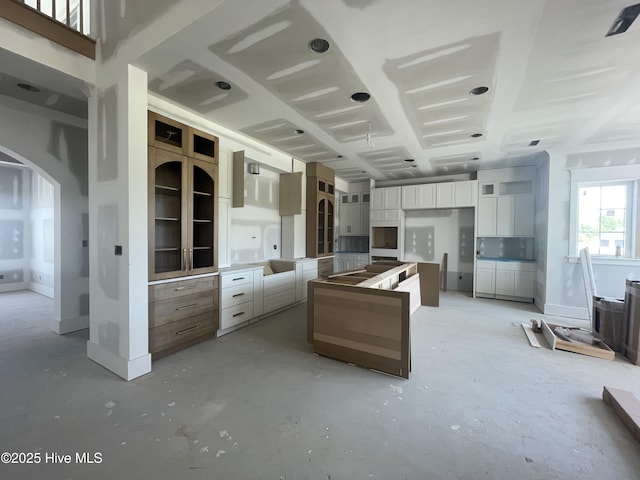 3413 Autumn Breeze Ct, Grimesland, NC 27837 - kitchen featuring concrete flooring, arched walkways, a kitchen island, and white cabinets