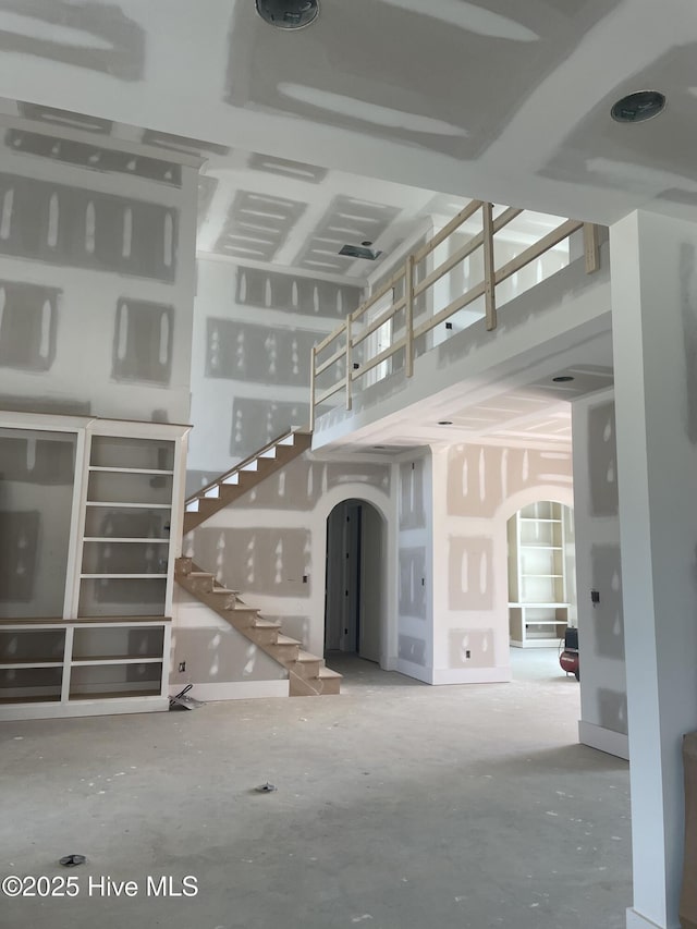 3413 Autumn Breeze Ct, Grimesland, NC 27837 - unfurnished living room with arched walkways, stairs, and a towering ceiling
