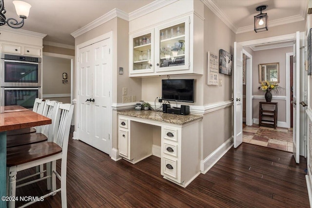 kitchen with white cabinets, dark stone countertops, ornamental molding, double oven, and dark hardwood / wood-style flooring