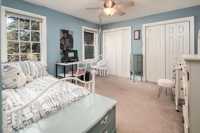 bedroom with carpet flooring, ceiling fan, and multiple closets