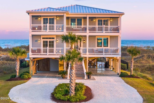 coastal home with a porch, a water view, and a carport