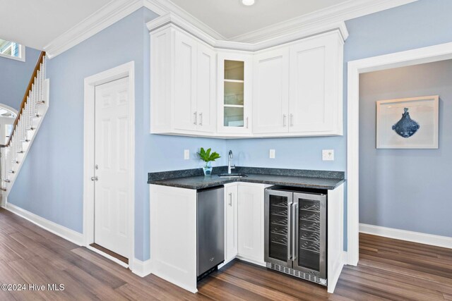 bar featuring sink, dark hardwood / wood-style floors, beverage cooler, crown molding, and white cabinets