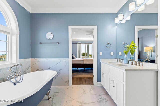 bathroom featuring tile walls, a bathtub, vanity, and crown molding