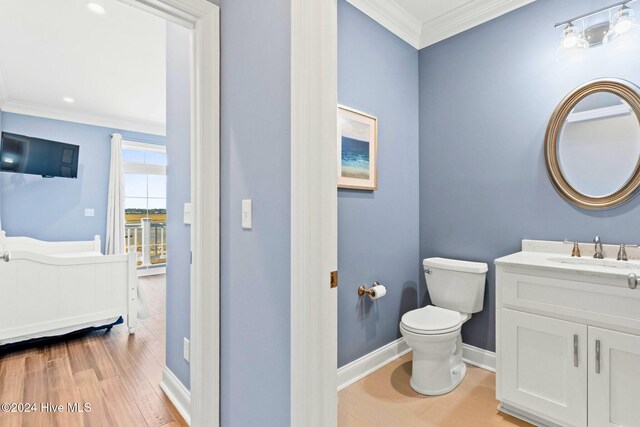 bathroom with crown molding, hardwood / wood-style floors, vanity, and toilet