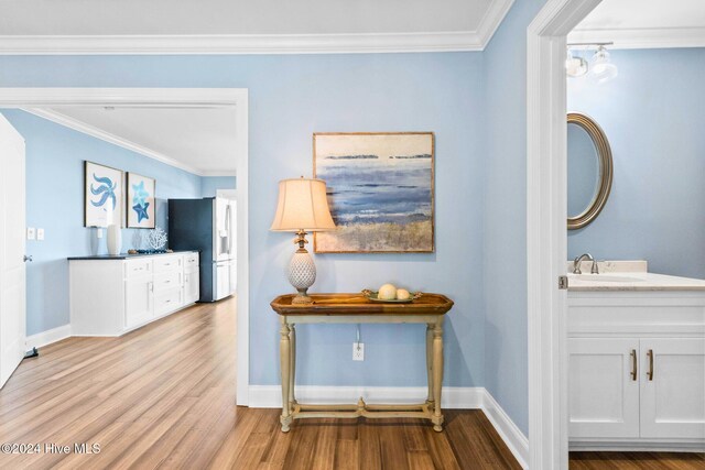 hall featuring light hardwood / wood-style floors, sink, and crown molding