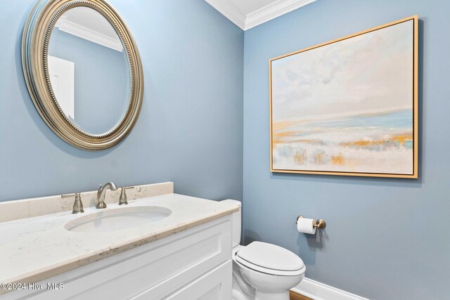 bathroom with ornamental molding, vanity, and toilet