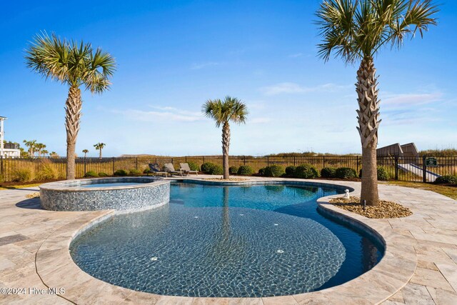 view of pool featuring a patio and an in ground hot tub