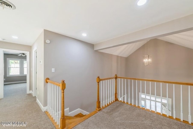 corridor featuring a chandelier, lofted ceiling with beams, and light colored carpet