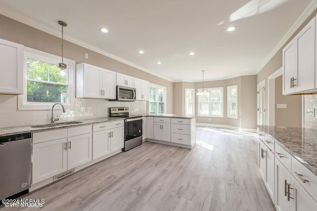 kitchen with sink, appliances with stainless steel finishes, decorative light fixtures, and white cabinets