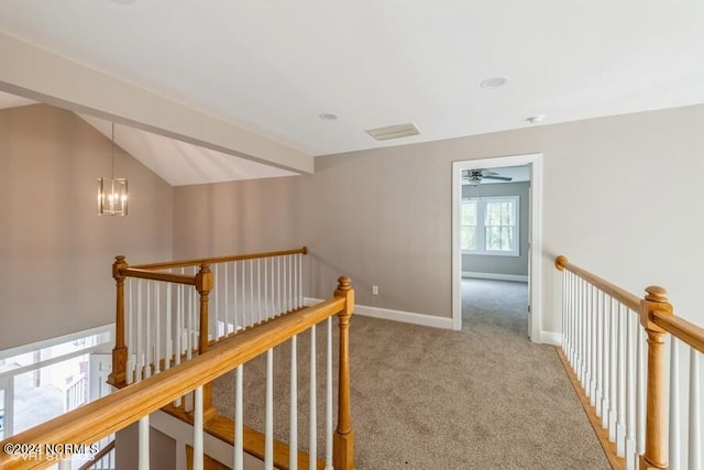 corridor with a notable chandelier, carpet, and vaulted ceiling