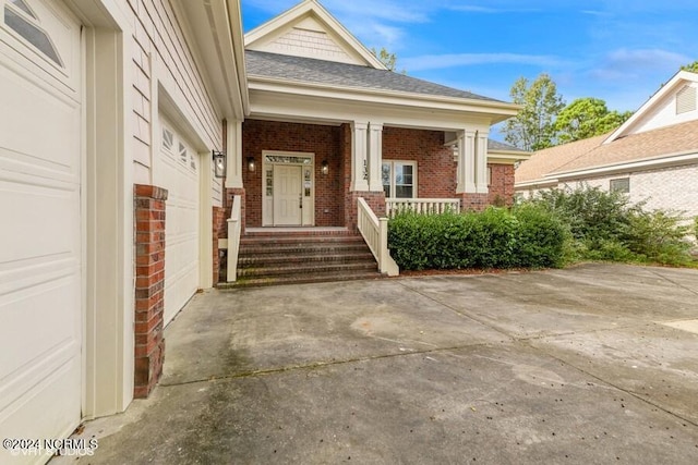 view of exterior entry with a porch and a garage