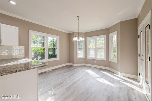 unfurnished dining area featuring light hardwood / wood-style floors, an inviting chandelier, and a wealth of natural light