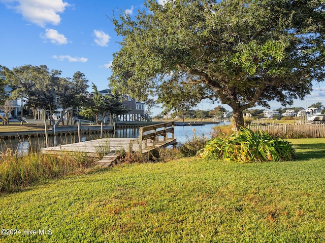 view of dock with a lawn and a water view