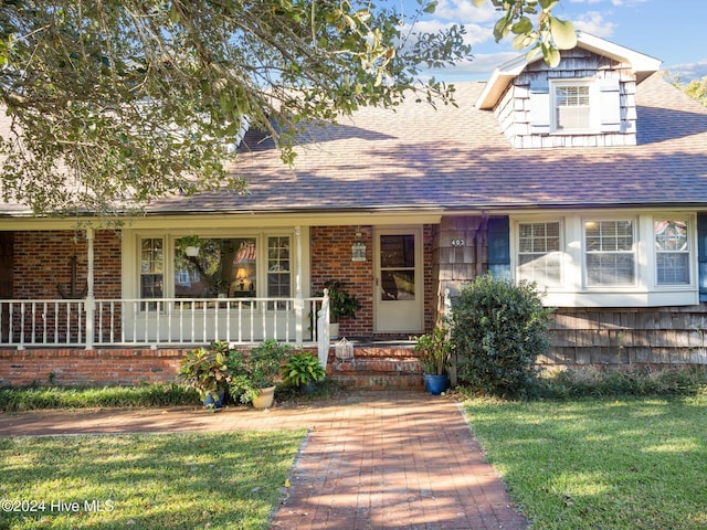 403 W Spring St, Swansboro, NC 28584 - view of front of house with a front lawn, roof with shingles, covered porch, and brick siding