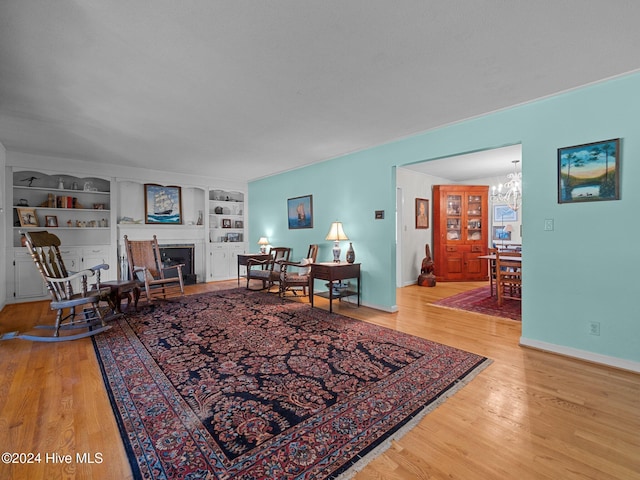 living room featuring built in features, a chandelier, and wood-type flooring