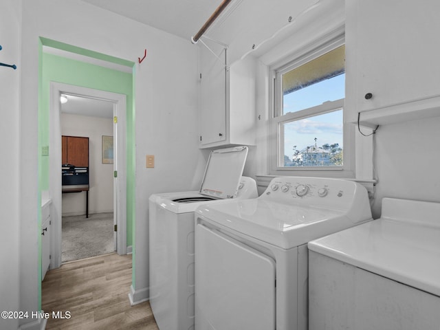 clothes washing area featuring cabinets, separate washer and dryer, and light wood-type flooring