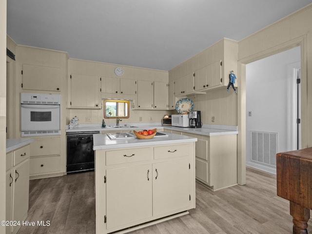 kitchen with a center island, dishwasher, oven, cream cabinetry, and light hardwood / wood-style flooring