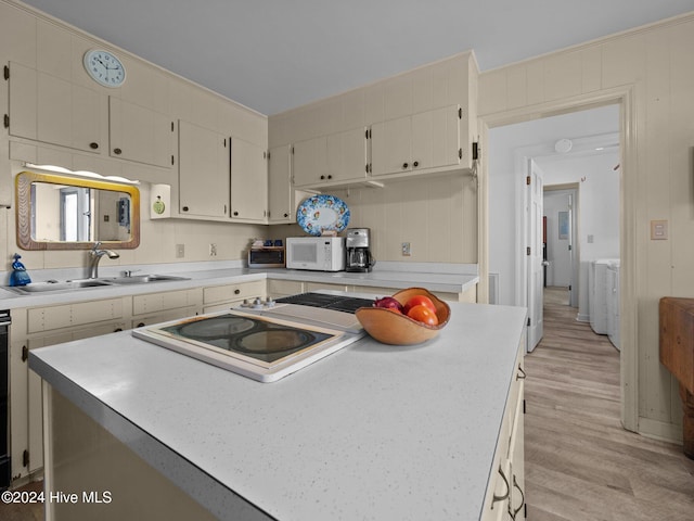 kitchen with sink, ornamental molding, a kitchen island, wooden walls, and light wood-type flooring