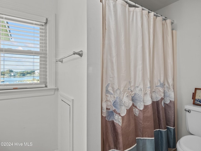 bathroom featuring a shower with curtain, toilet, and a water view