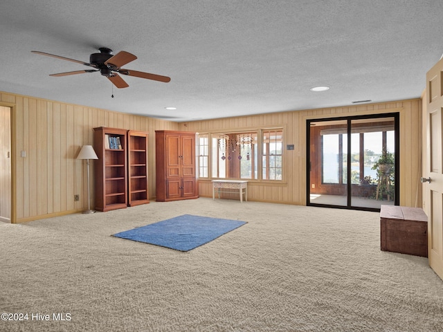 interior space with wooden walls, a textured ceiling, and carpet