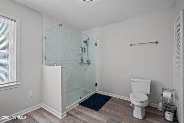 bathroom with a textured ceiling, wood-type flooring, toilet, and walk in shower