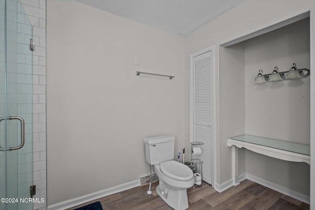 bathroom with a textured ceiling, a shower with shower door, wood-type flooring, and toilet