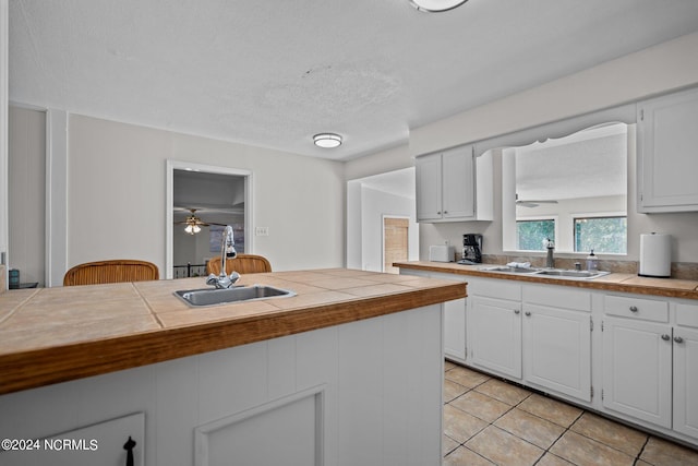 kitchen featuring white cabinetry, tile countertops, and sink