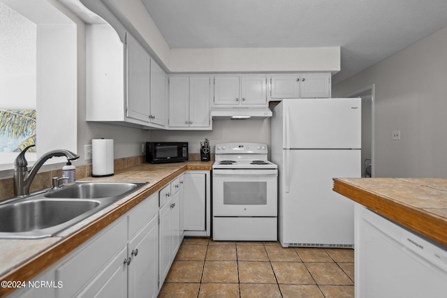 kitchen featuring white appliances, sink, white cabinetry, tile counters, and light tile patterned floors