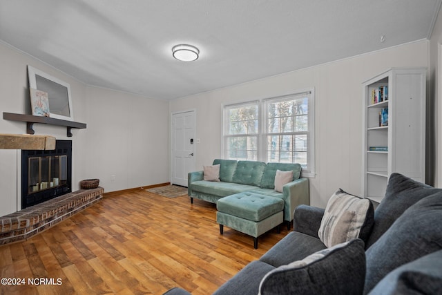 living room featuring crown molding, a brick fireplace, wood-type flooring, and a textured ceiling