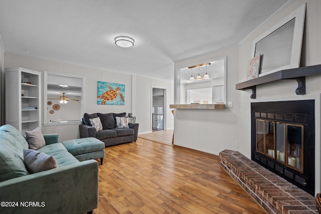 living room with ceiling fan, a textured ceiling, a fireplace, and hardwood / wood-style floors