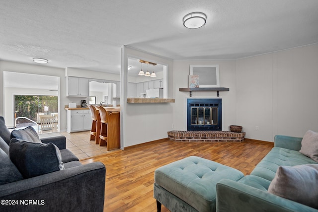 living room featuring a fireplace, a textured ceiling, and light wood-type flooring