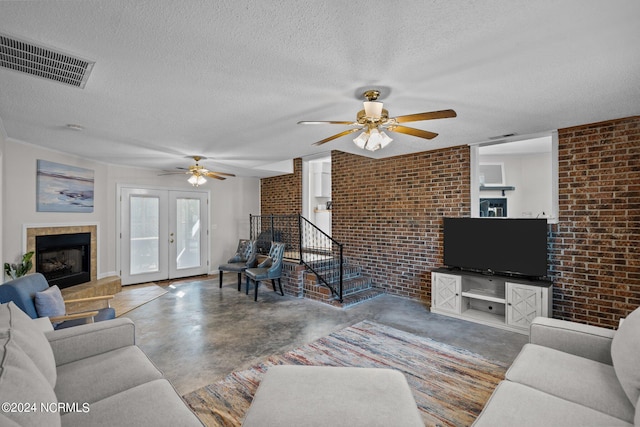 living room with brick wall, french doors, a textured ceiling, and concrete floors