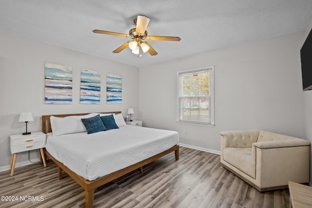 bedroom featuring ceiling fan, hardwood / wood-style flooring, and a textured ceiling