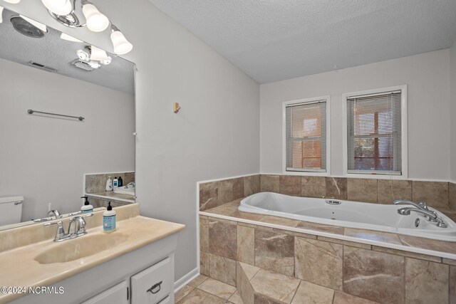 bathroom featuring vanity, a textured ceiling, tiled tub, and tile patterned flooring