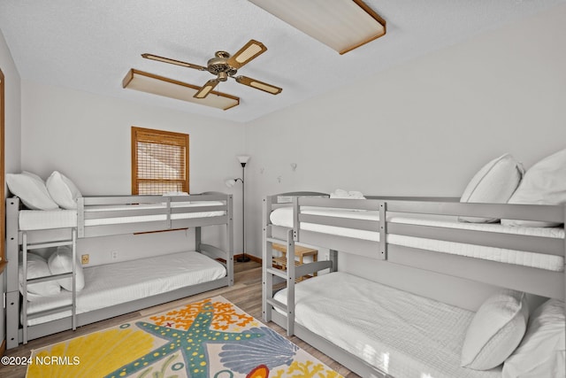 bedroom with ceiling fan, hardwood / wood-style flooring, and a textured ceiling