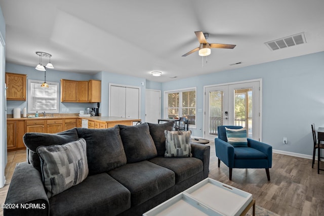 living room featuring sink, french doors, light hardwood / wood-style flooring, and ceiling fan