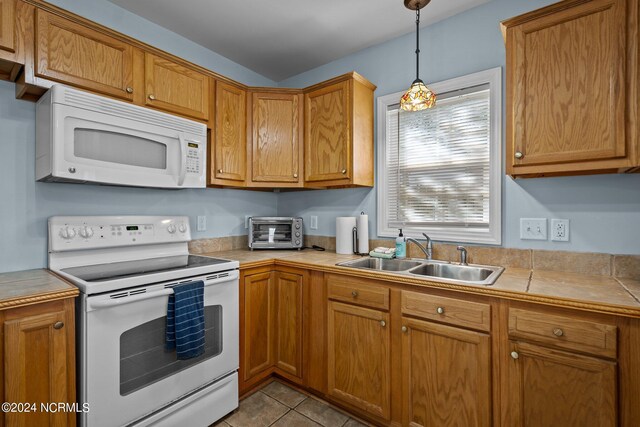 kitchen featuring decorative light fixtures, sink, light tile patterned floors, and white appliances