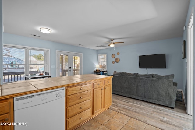 kitchen with ceiling fan, white dishwasher, light hardwood / wood-style flooring, tile counters, and french doors