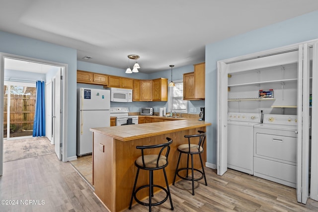 kitchen with white appliances, a healthy amount of sunlight, washer and clothes dryer, and pendant lighting