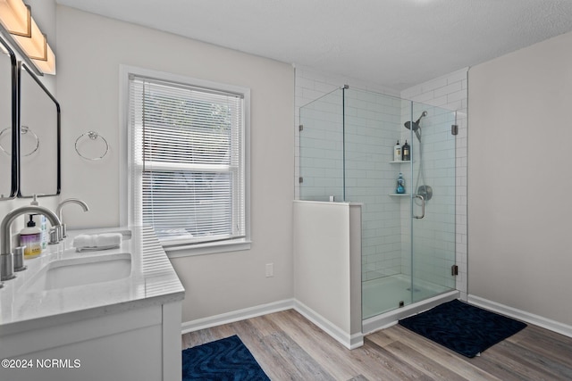 bathroom featuring vanity, a textured ceiling, an enclosed shower, and hardwood / wood-style floors