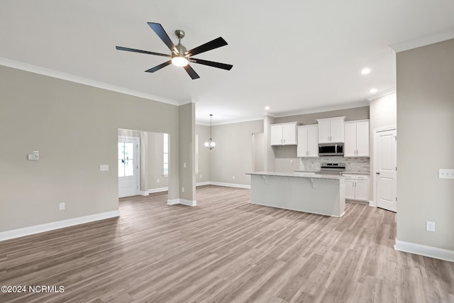 kitchen with a center island with sink, crown molding, white cabinetry, appliances with stainless steel finishes, and light hardwood / wood-style floors