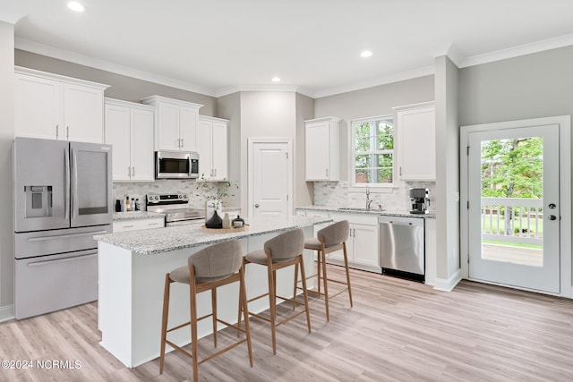 kitchen with light hardwood / wood-style flooring, stainless steel appliances, a center island, and white cabinets