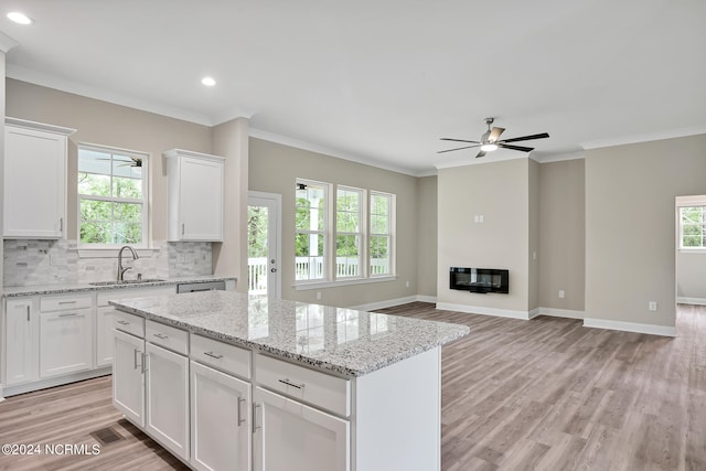 kitchen featuring a kitchen island, light hardwood / wood-style flooring, sink, white cabinets, and light stone counters