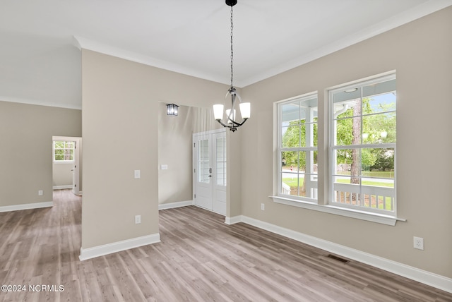 unfurnished dining area with light hardwood / wood-style floors, crown molding, and an inviting chandelier