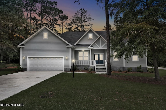 view of front of property featuring a yard, a porch, and a garage