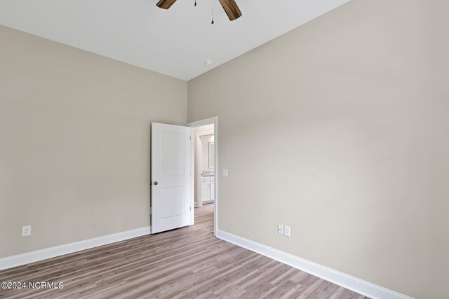 empty room featuring light hardwood / wood-style floors, a high ceiling, and ceiling fan