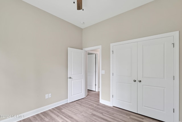 unfurnished bedroom featuring a closet, light hardwood / wood-style floors, and ceiling fan